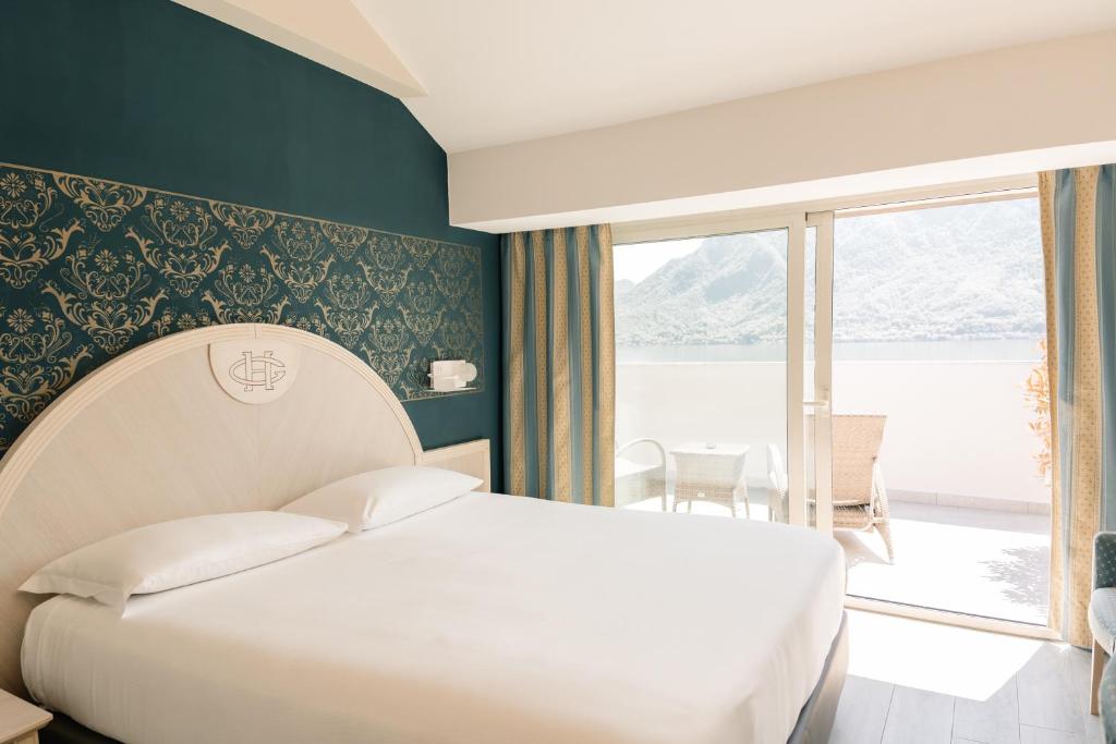 une chambre avec un lit blanc et une grande fenêtre dans l'établissement Hotel Ghiffa, à Ghiffa