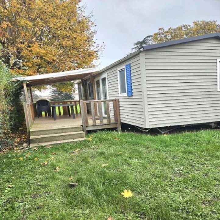 une petite maison avec un porche et une terrasse dans l'établissement Camping de Charlieu - Mobile home, à Charlieu