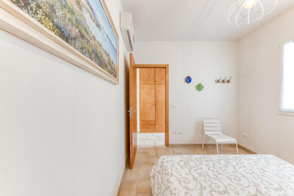 une chambre blanche avec un lit et une chaise dans l'établissement Perla sul mare Adriatico, à Marittima