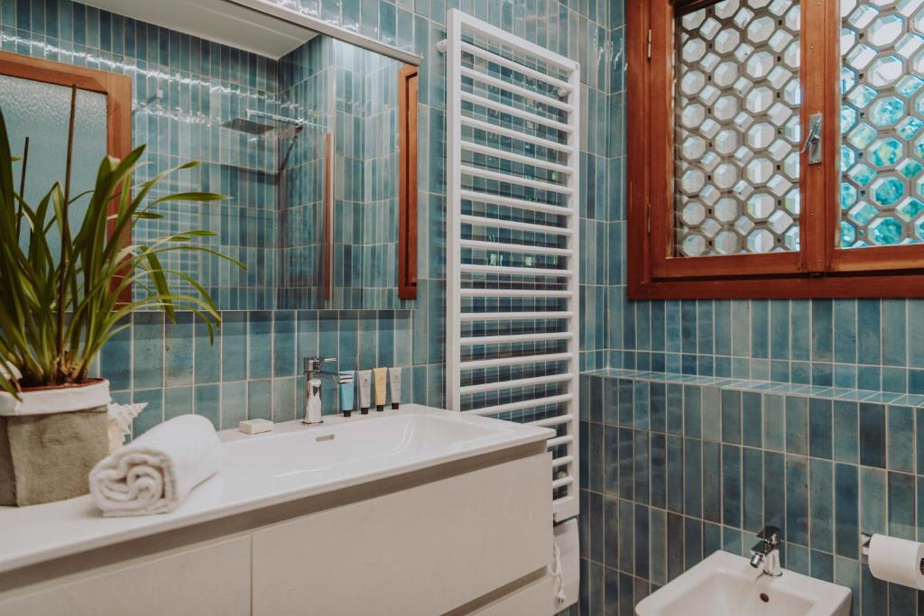La salle de bains est pourvue de carrelage bleu, d'un lavabo et d'un miroir. dans l'établissement Holiday Garda Villa Dolcelago Lake Front, à Moniga del Garda