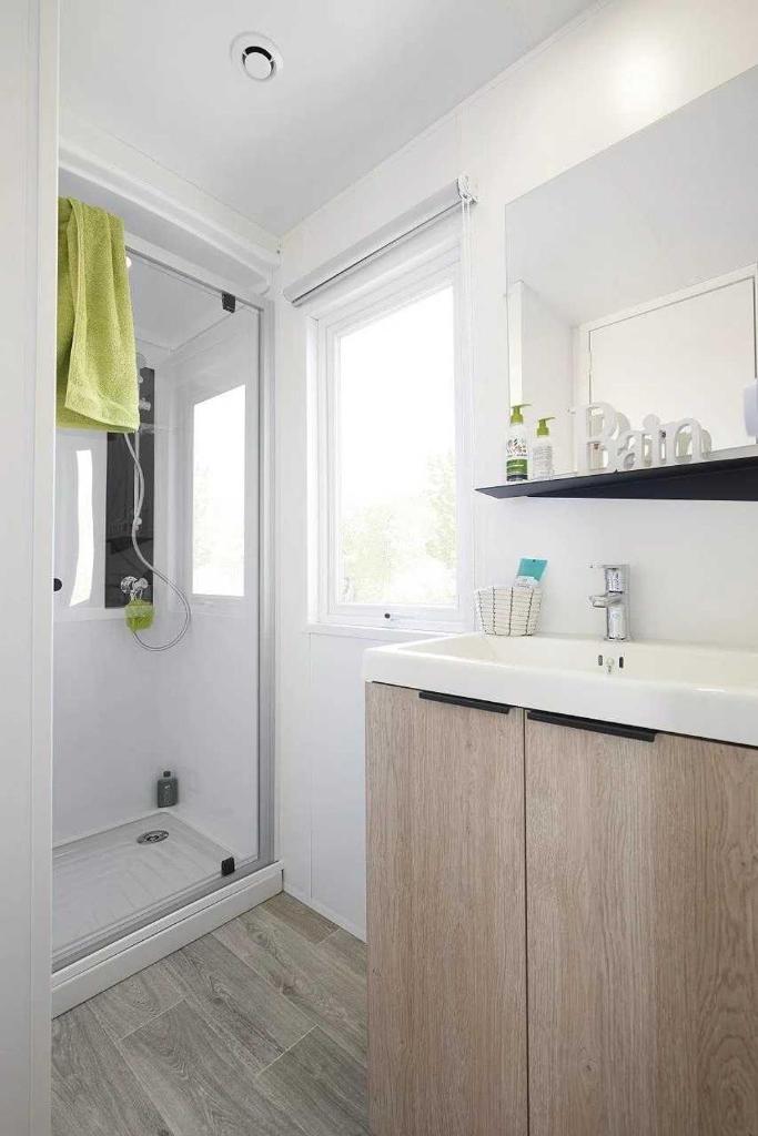 une salle de bain avec un lavabo, un miroir et une douche dans l'établissement Camping 3 étoiles - Piscine - eecbb0, à Guérande