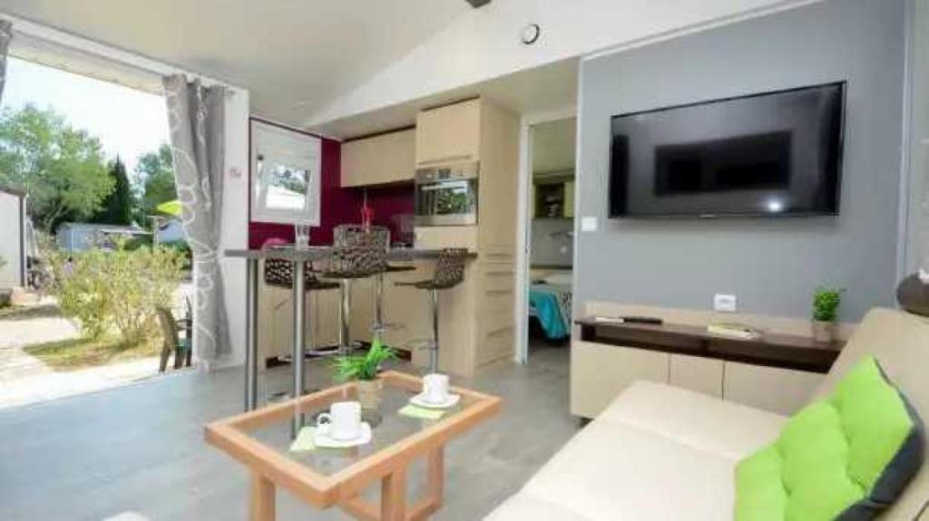 un salon avec un canapé et une télévision sur un mur dans l'établissement Camping 4 étoiles - Parc aquatique - eece0c, à Grimaud