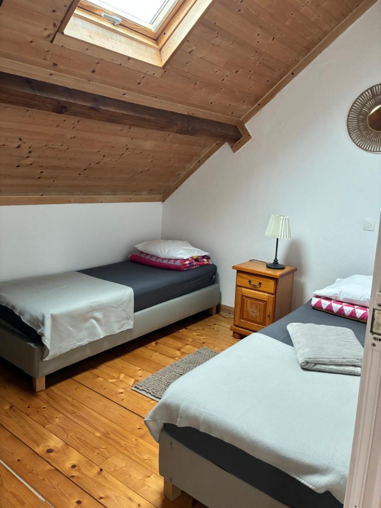une chambre avec deux lits et une lucarne dans l'établissement Gîte au Bon Accueil Therence, à Sainte-Thérence