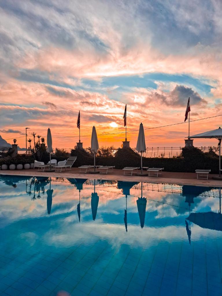 une piscine avec un coucher de soleil en arrière-plan dans l'établissement Hotel Sirenetta, à Isola delle Femmine