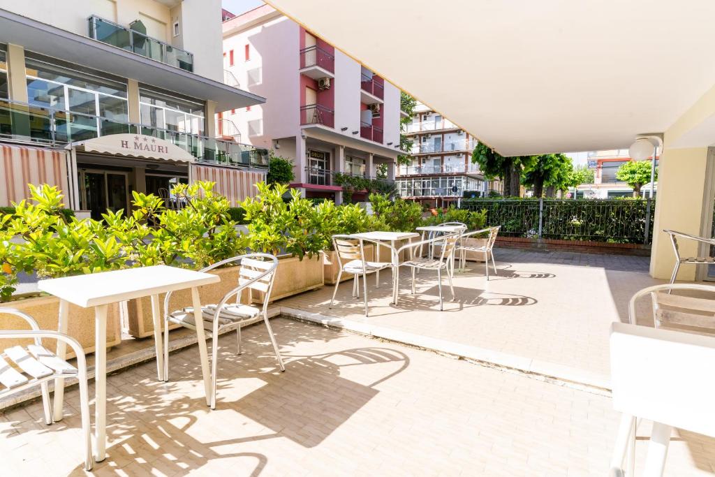 un patio avec tables et chaises dans un bâtiment dans l'établissement Hotel Ischia, à Rimini