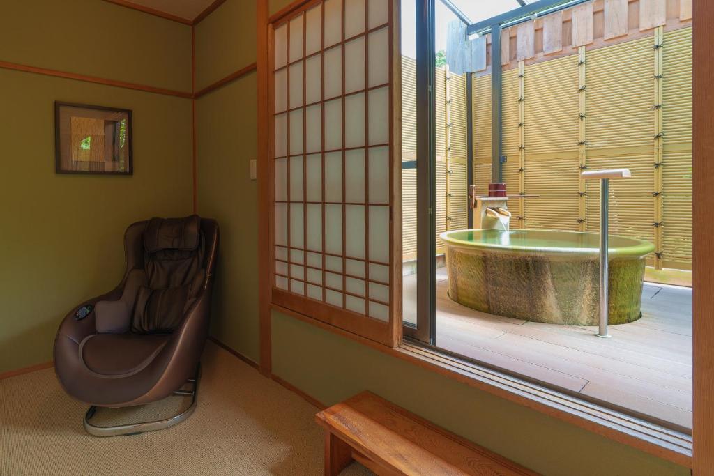 Cette chambre dispose d'une fenêtre avec une baignoire et une chaise. dans l'établissement Gyokusui -Adult Only-, à Higashiizu