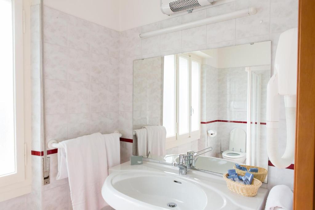 une salle de bain blanche avec un lavabo et un miroir dans l'établissement Club Hotel Olivi - Tennis Center, à Malcesine