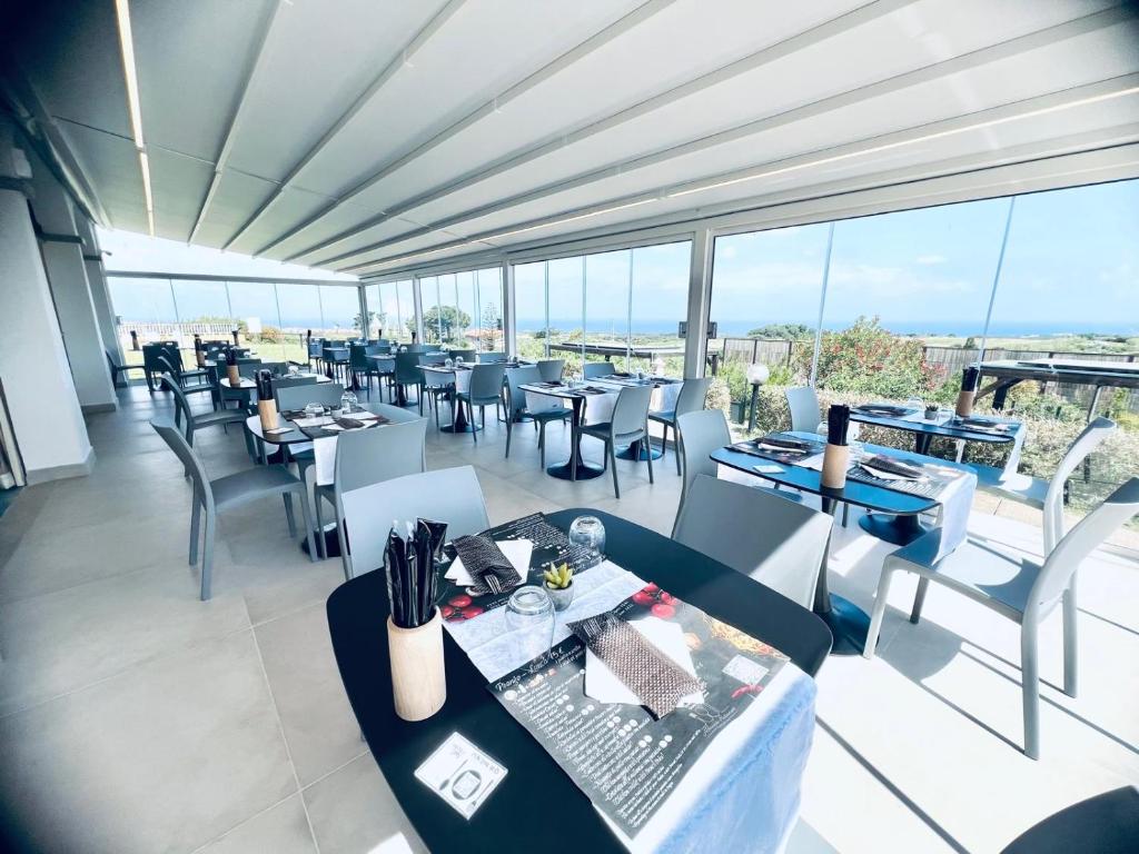 une salle à manger avec tables, chaises et fenêtres dans l'établissement Abbaidda Hotel, à Valledoria