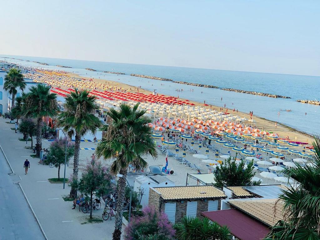 - une plage avec de nombreux parasols et des personnes sur la plage dans l'établissement Hotel La Perla, à Cupra Marittima