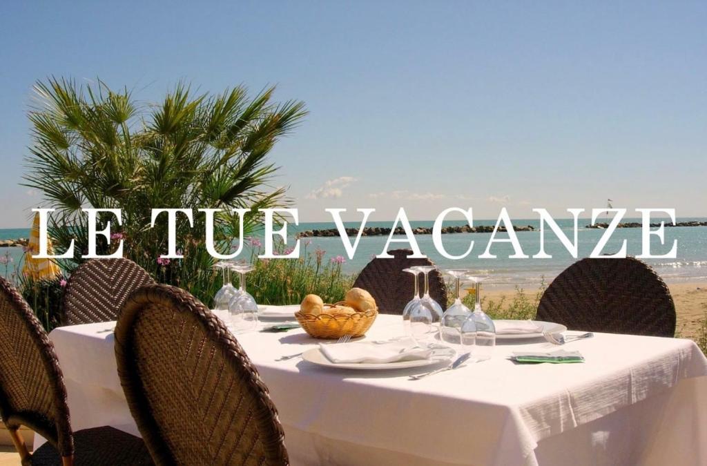 une table avec une nappe blanche sur une plage dans l'établissement Hotel La Perla, à Cupra Marittima