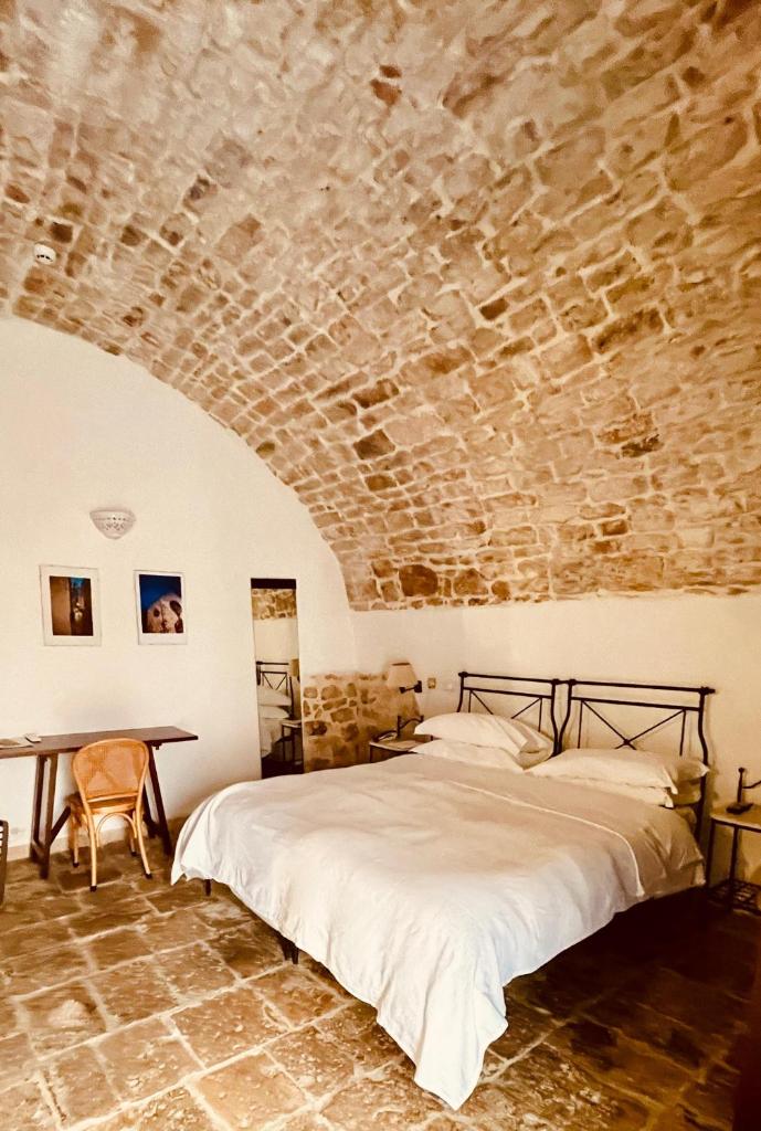 une chambre avec un lit et un mur en pierre dans l'établissement Hotel Corte Altavilla, à Conversano
