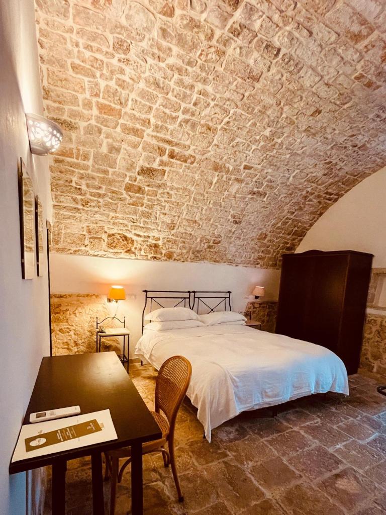 une chambre avec un lit et un mur en pierre dans l'établissement Hotel Corte Altavilla, à Conversano