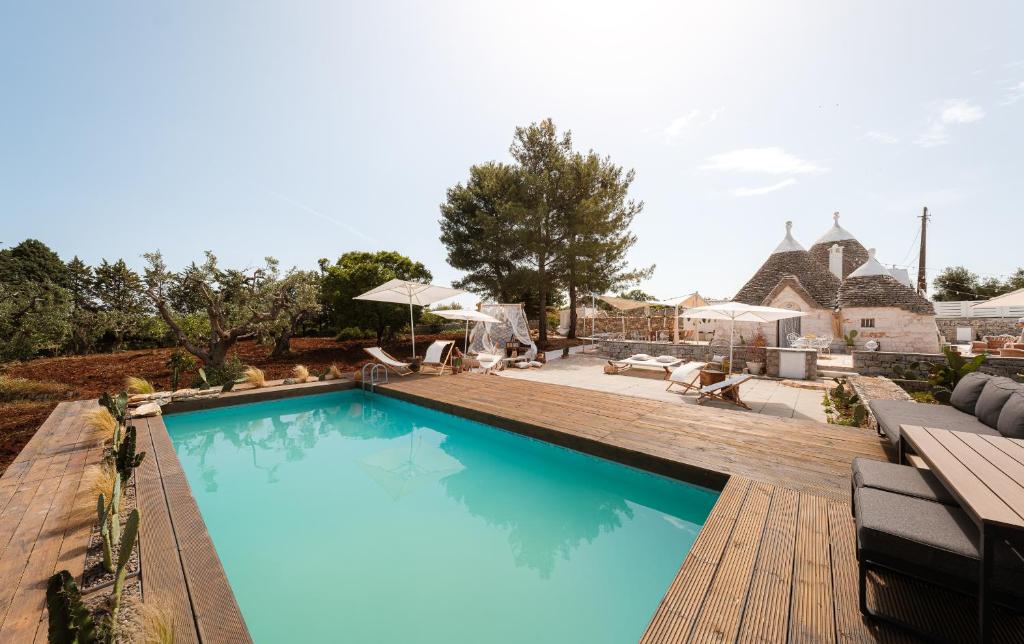une piscine avec une terrasse en bois et une maison dans l'établissement Trulli di Mamma Marì by STHEY, à Castellana Grotte