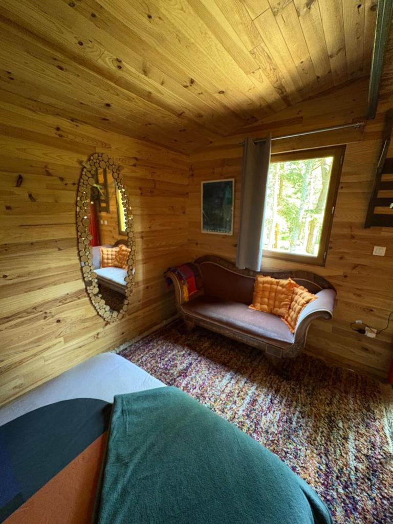 une chambre avec un canapé dans une cabane en rondins dans l'établissement Chalet Cricri Domaine de la Mamounette, à Champclause