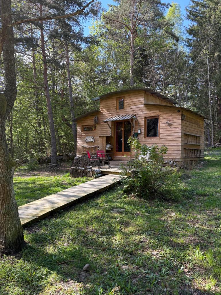 une cabane en rondins dans les bois avec une passerelle en bois dans l'établissement Chalet Cricri Domaine de la Mamounette, à Champclause