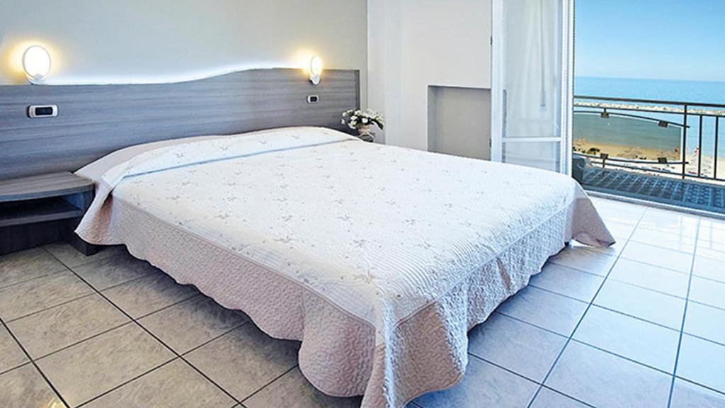 une chambre avec un lit et une vue sur l'océan dans l'établissement Hotel La Perla, à Cupra Marittima