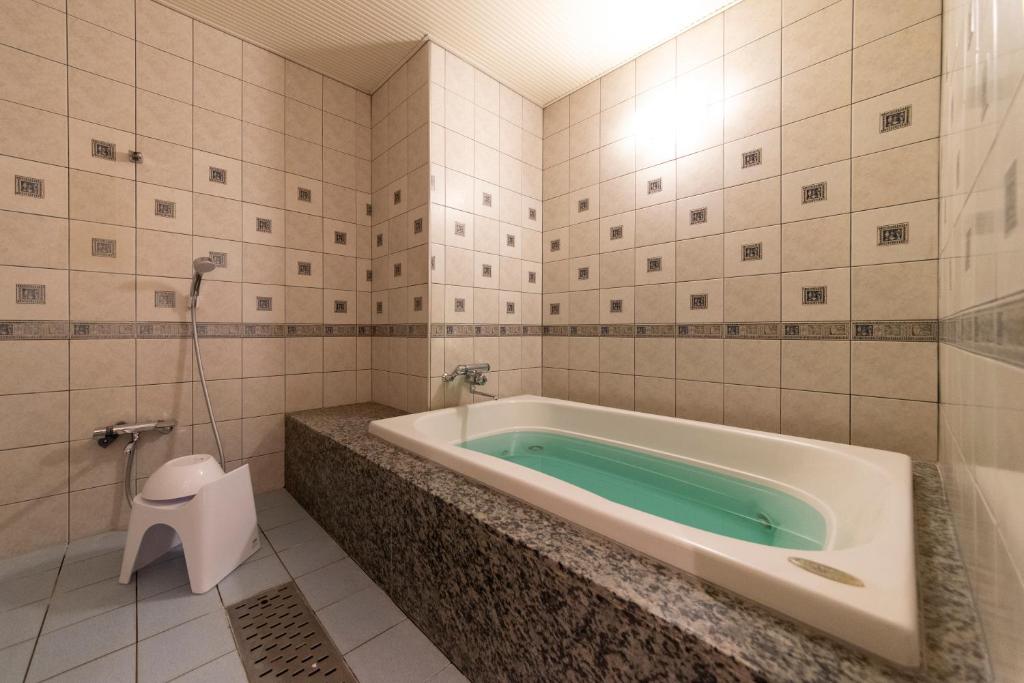 une baignoire dans une salle de bain avec toilettes dans l'établissement ホテルネオワカバ, à Tsuchiura