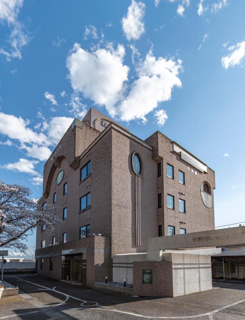 un bâtiment en briques brunes avec un ciel en arrière-plan dans l'établissement ホテルネオワカバ, à Tsuchiura