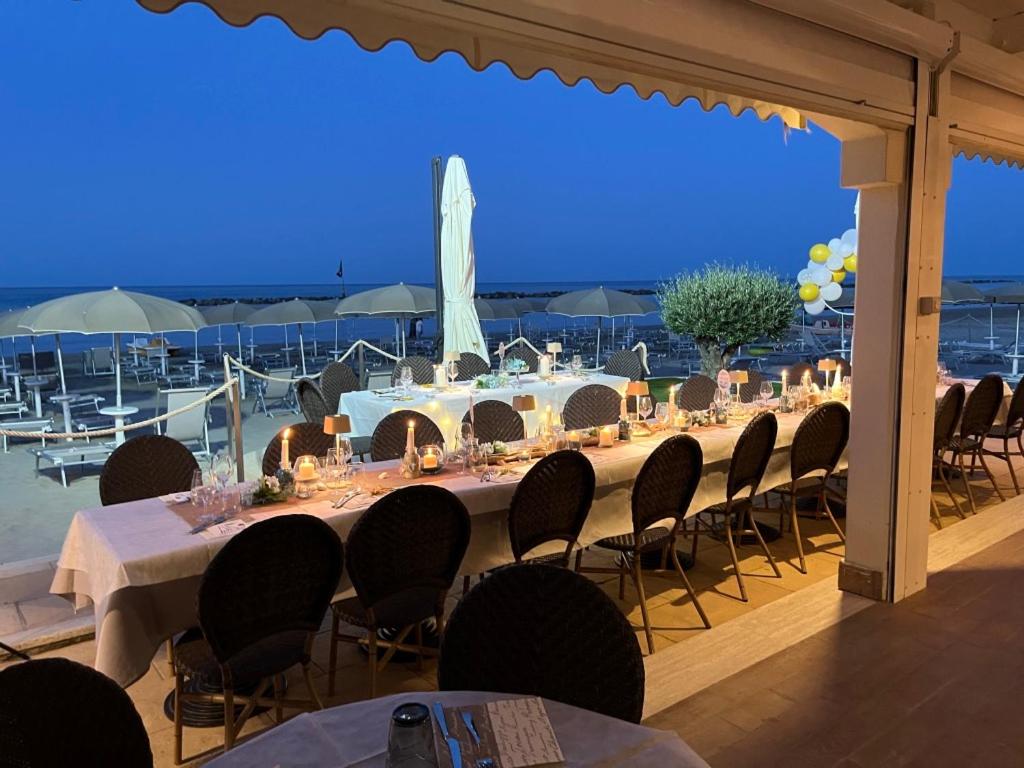 une grande table avec des chaises et une vue sur l'océan dans l'établissement Hotel La Perla, à Cupra Marittima
