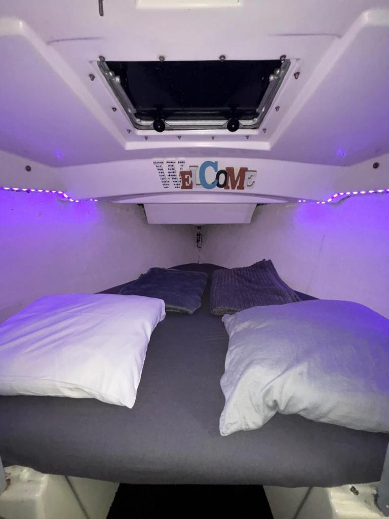 Ce lit se trouve dans un dortoir doté de lumières violettes. dans l'établissement Voilier Port Deauville avec parking privé gratuit, à Deauville
