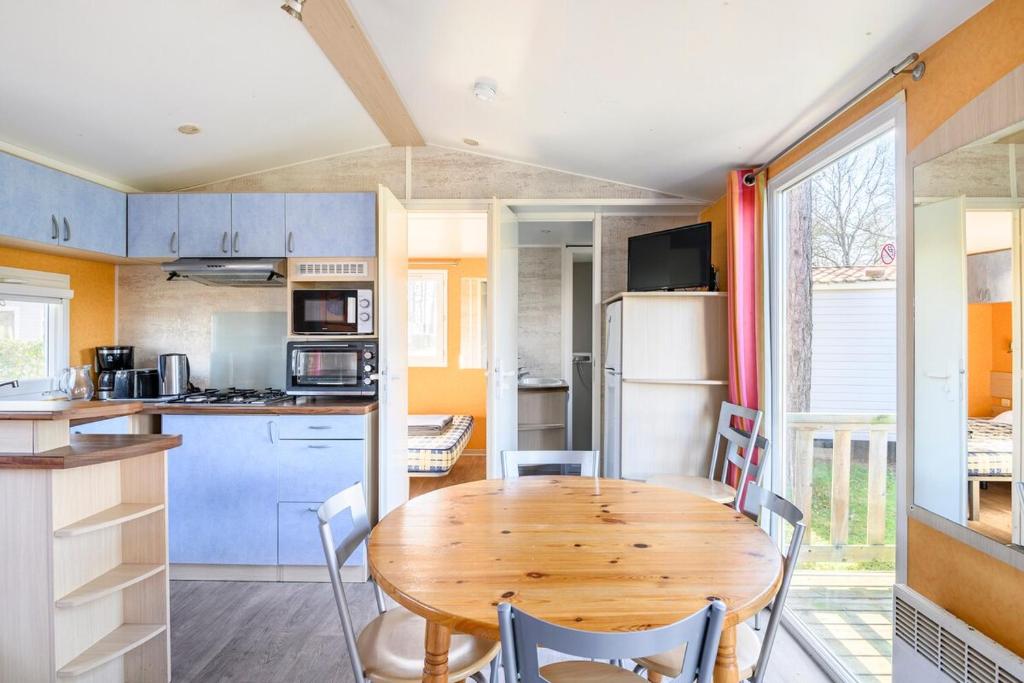 - une cuisine avec une table en bois et des chaises dans une caravane dans l'établissement Mobil-home 6 personnes 3 chambres, à La Boissière-de-Montaigu