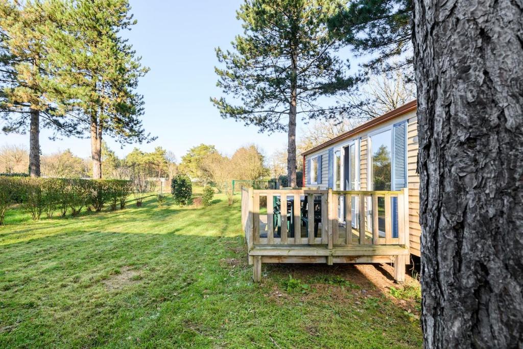 une maison en bois avec un porche à côté d'un arbre dans l'établissement Mobil-home 6 personnes 3 chambres, à La Boissière-de-Montaigu