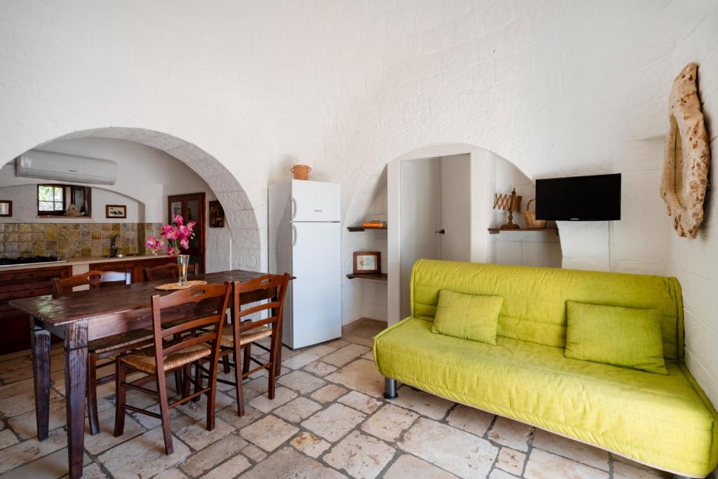 un salon avec un canapé jaune et une table dans l'établissement Villa Trullo Ulivo with pool, à Carovigno