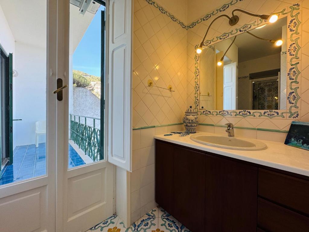 La salle de bains est pourvue d'un lavabo, d'un miroir et d'un balcon. dans l'établissement YourHome - Villa Ayala, à Vico Equense
