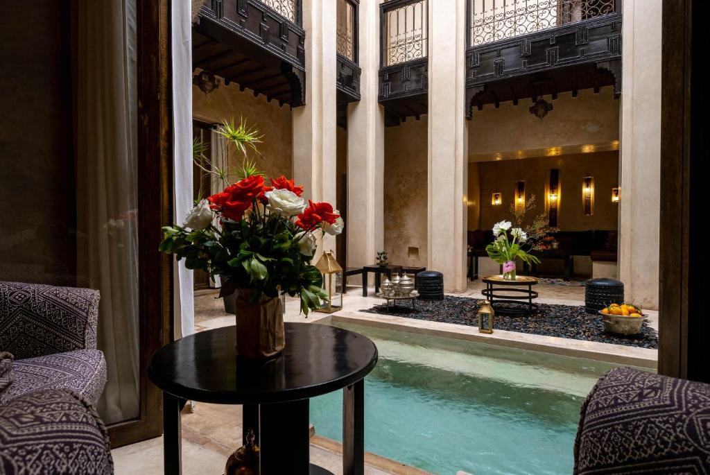un vase de fleurs sur une table à côté d'une piscine dans l'établissement Riad Vanilla Sma & Spa, à Marrakech 37 autres photos