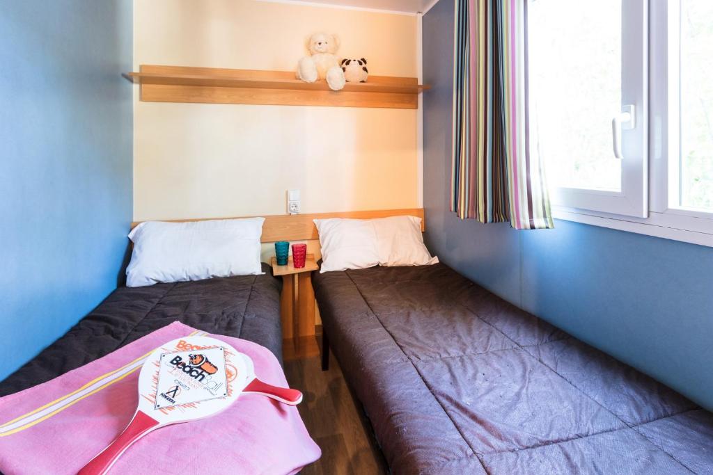 une petite chambre avec deux lits et une fenêtre dans l'établissement Camping La Palmeraie, à Torreilles