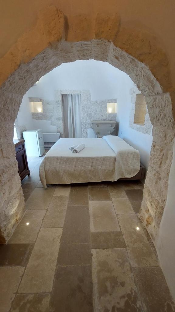 une chambre avec un grand lit dans un mur de pierre dans l'établissement Trullo Terra Bianca, à Ostuni