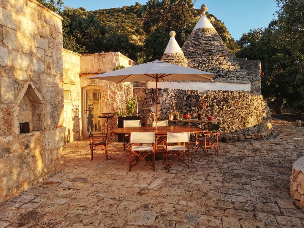 une table et des chaises avec un parasol sur une terrasse dans l'établissement Eremo di San Giusto - Trullo Vista Mare, à Ostuni