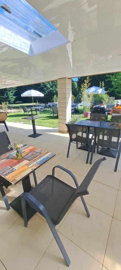 un patio avec des tables, des chaises et des parasols dans l'établissement Camping Les Galets, à Banassac