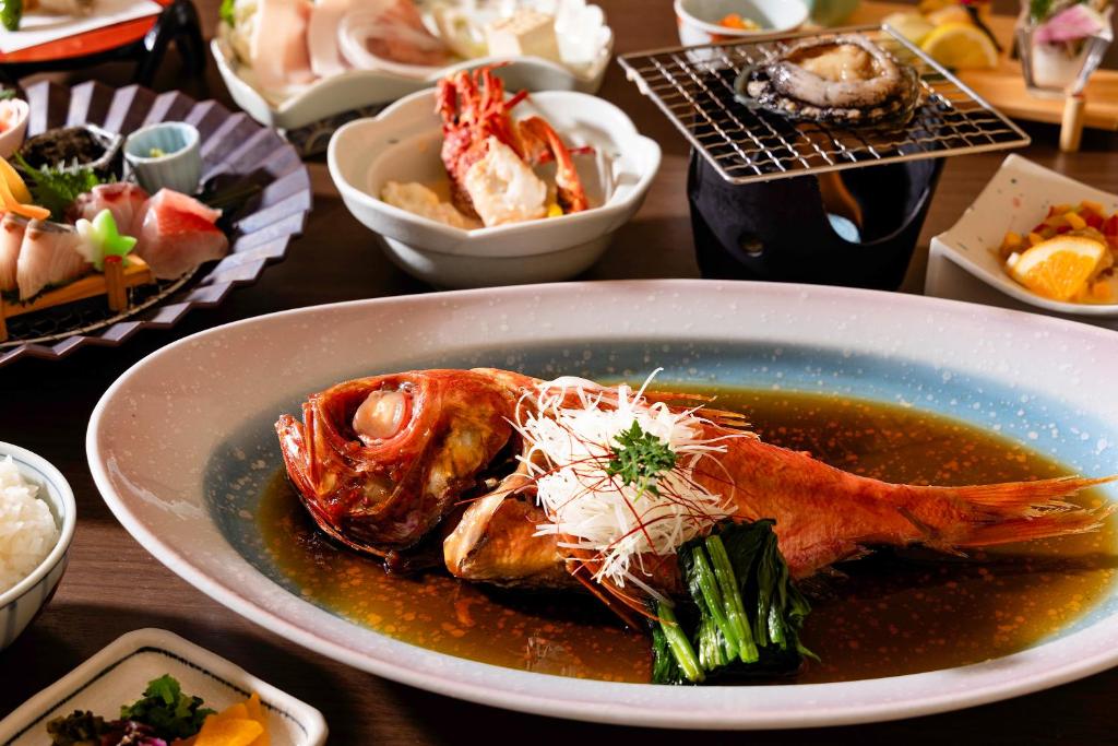 une table avec une assiette de nourriture avec un poulet au bouillon dans l'établissement Shinyu no Yado SAZANA, à Higashiizu
