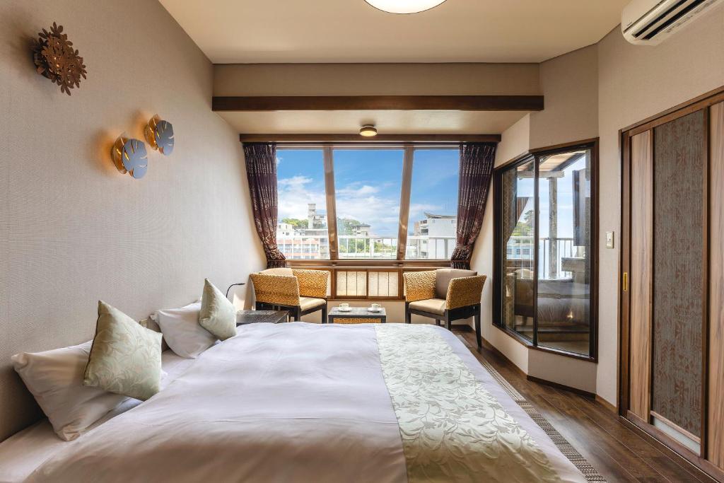 une chambre d'hôtel avec un lit et une grande fenêtre dans l'établissement Shinyu no Yado SAZANA, à Higashiizu