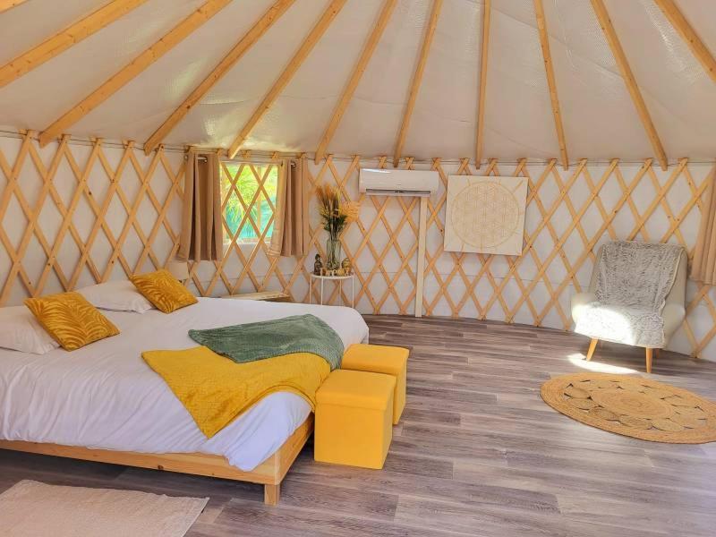 - une chambre dans une yourte avec un lit et une chaise dans l'établissement D'EMILION De SENS, à Gardegan-et-Tourtirac