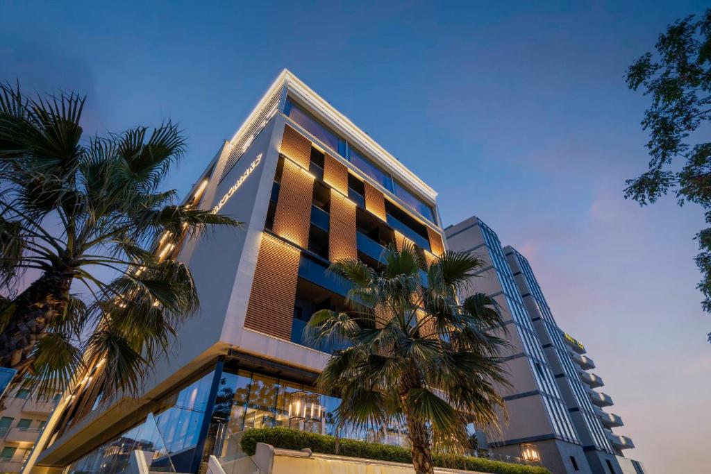 un grand bâtiment avec des palmiers devant dans l'établissement Hotel Lungomare, à Riccione