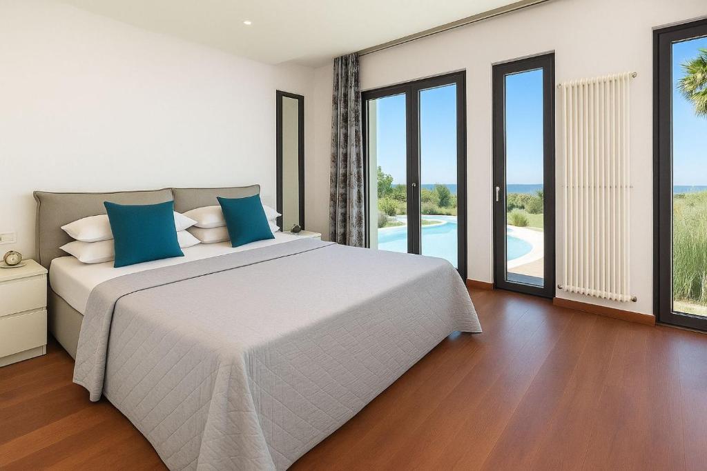 une chambre avec un grand lit blanc avec des oreillers bleus dans l'établissement Villa Flavia, à Polignano a Mare