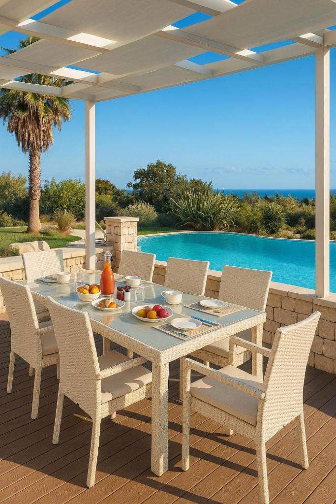 une table et des chaises blanches sur une terrasse avec piscine dans l'établissement Villa Flavia, à Polignano a Mare 4 autres photos