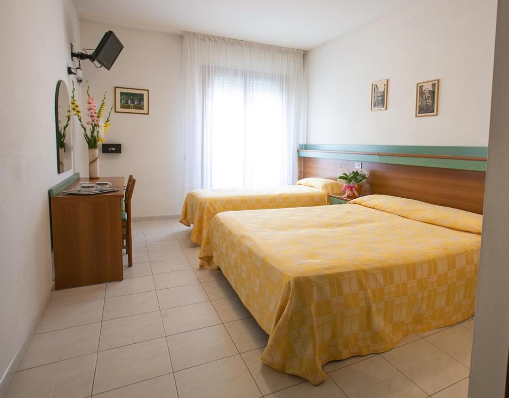 une chambre d'hôtel avec deux lits et une table dans l'établissement Hotel Grand Prix, à Sottomarina