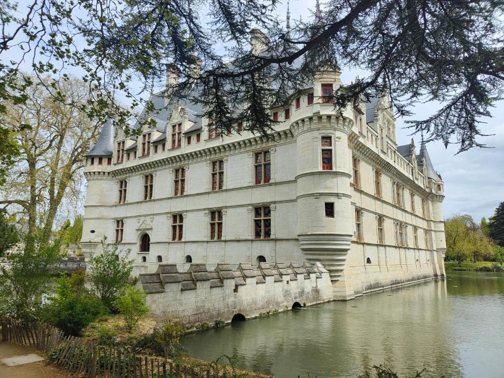 un grand bâtiment blanc au sommet d'une rivière dans l'établissement Gîte Pause au jardin piscine chauffée, à Saint-Branchs