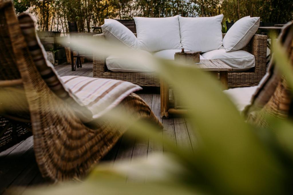 - un ensemble de chaises et d'oreillers en osier sur une terrasse dans l'établissement Hotel Saraceno Resort with Private Beach, à Milano Marittima