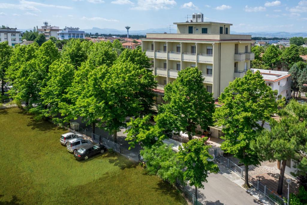 une vue aérienne sur un bâtiment avec des voitures garées dans un parc dans l'établissement Hotel Gattuccio, à Cesenatico