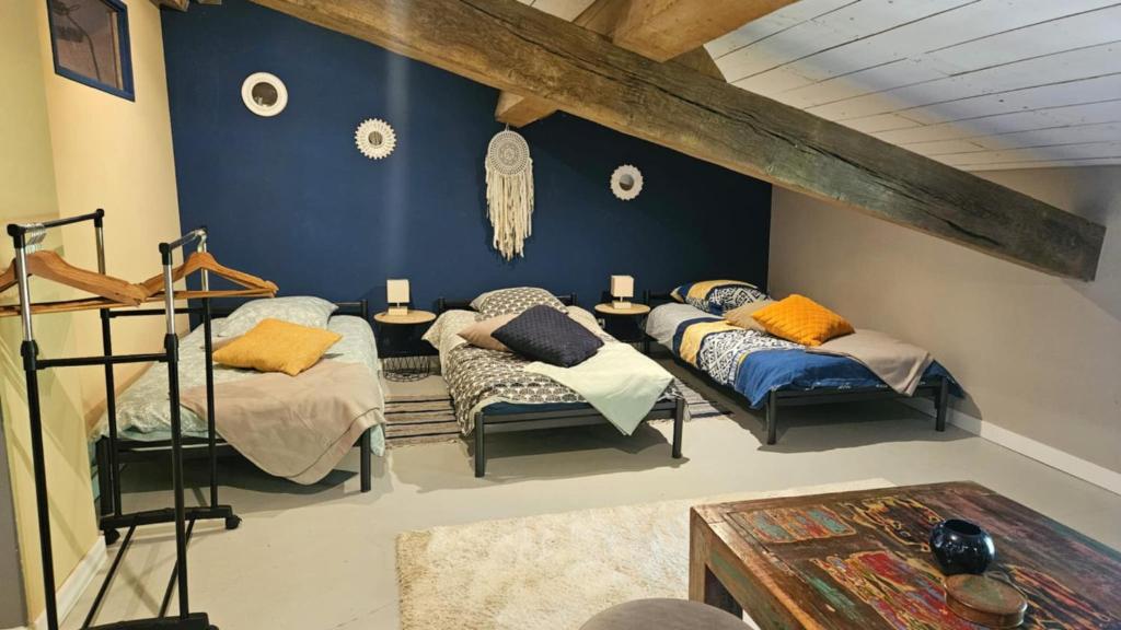 Cette chambre comprend 3 lits et un mur bleu. dans l'établissement Gîte des écuries de la paguere, à Aurignac