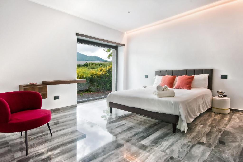 une chambre avec un grand lit et une chaise rouge dans l'établissement Villa dei Gelsomini, à Rocca di Papa