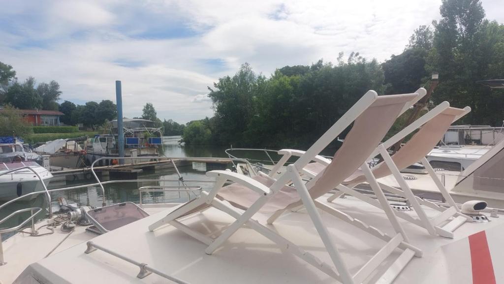 2 chaises blanches assises à l'arrière d'un bateau dans l'établissement Escapade en Bateau VINTAGE terrasse mini spa option payante, à Seurre 4 autres photos