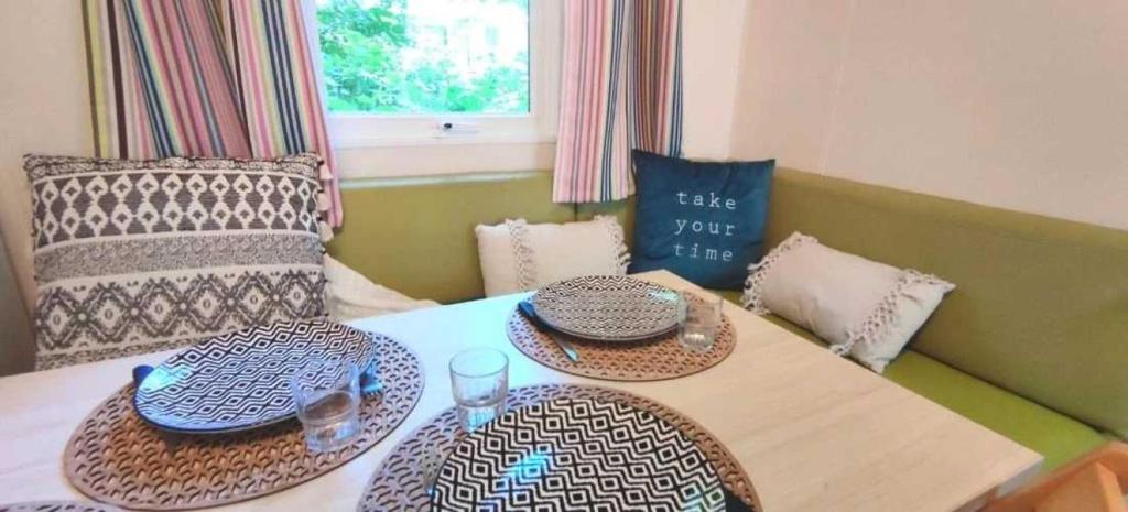 - une table à manger avec deux assiettes et des verres dans l'établissement Camping 4 étoiles - Piscine - eeiige, à Saint-Pardoux