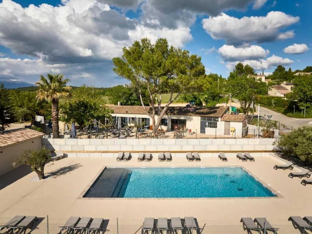 une piscine avec des chaises longues et un complexe hôtelier dans l'établissement Camping 3 étoiles - Piscine - efaeh0, à Malemort-du-Comtat