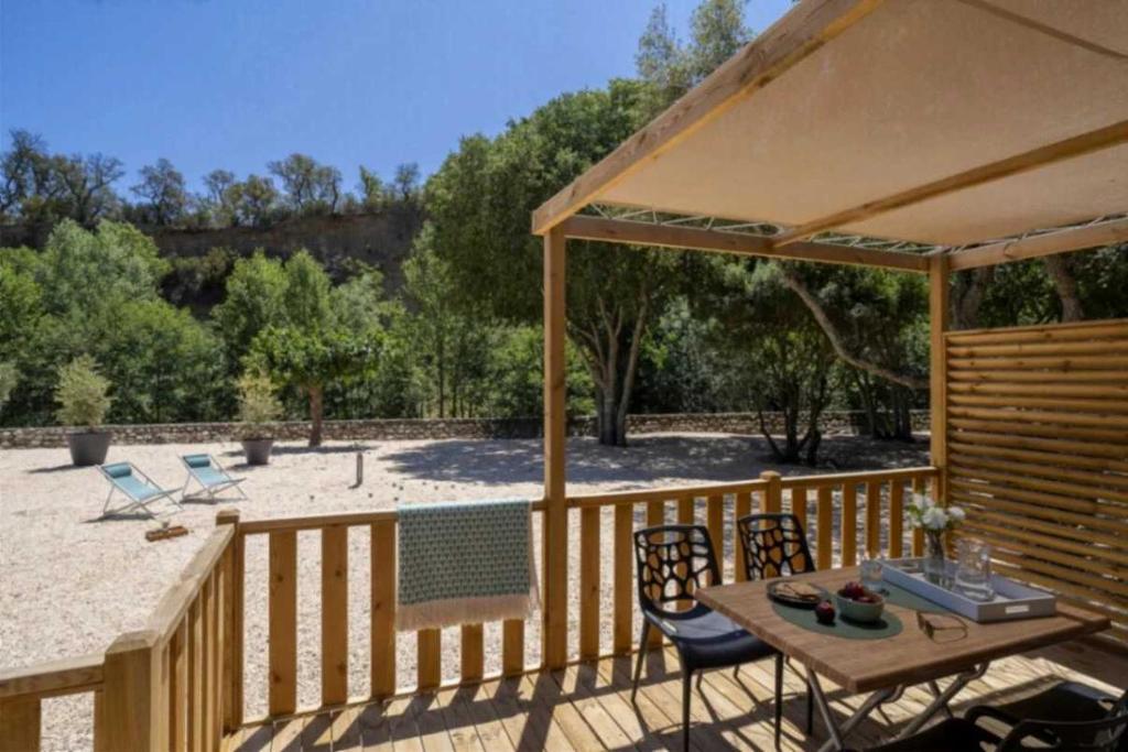 une terrasse en bois avec une table et des chaises sous un parasol dans l'établissement Camping - Piscine - ccai0bg, à Argelès-sur-Mer