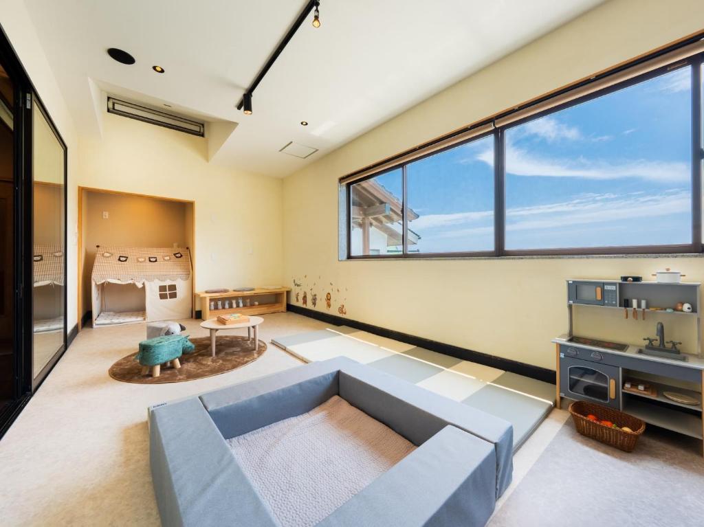 - un salon avec un canapé bleu et de grandes fenêtres dans l'établissement Kannawaen, à Beppu